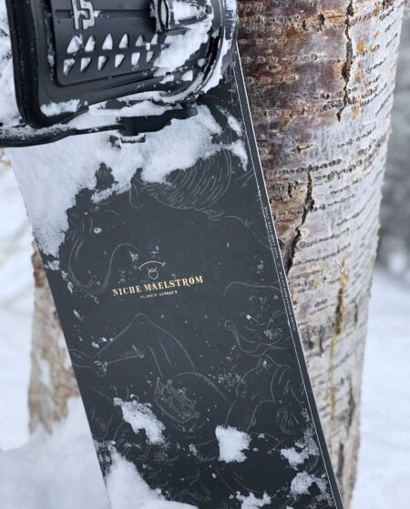 niche snowboards maelstrom leaning against tree